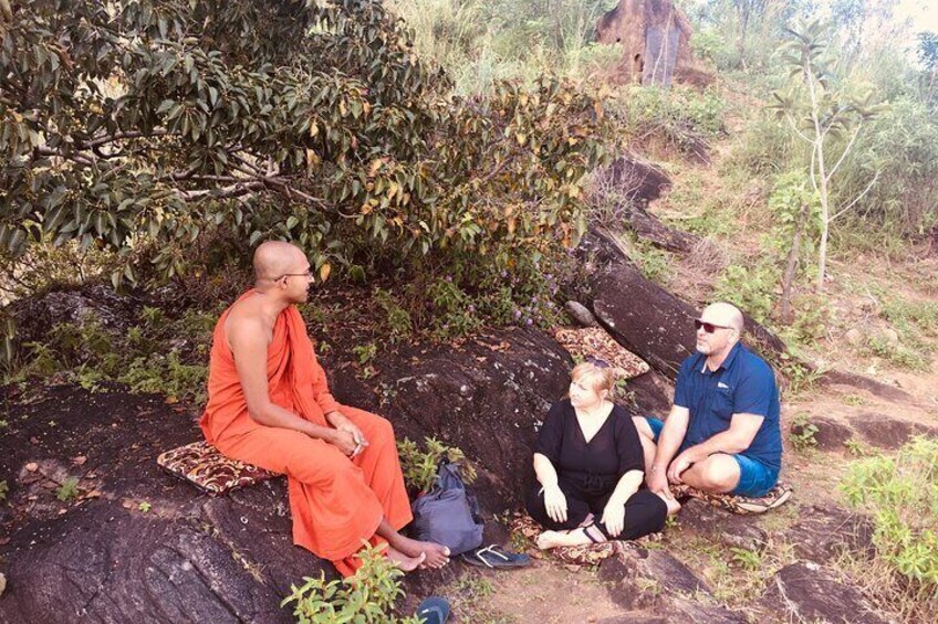 Three people sitting on a rock with a tree in the background. 3