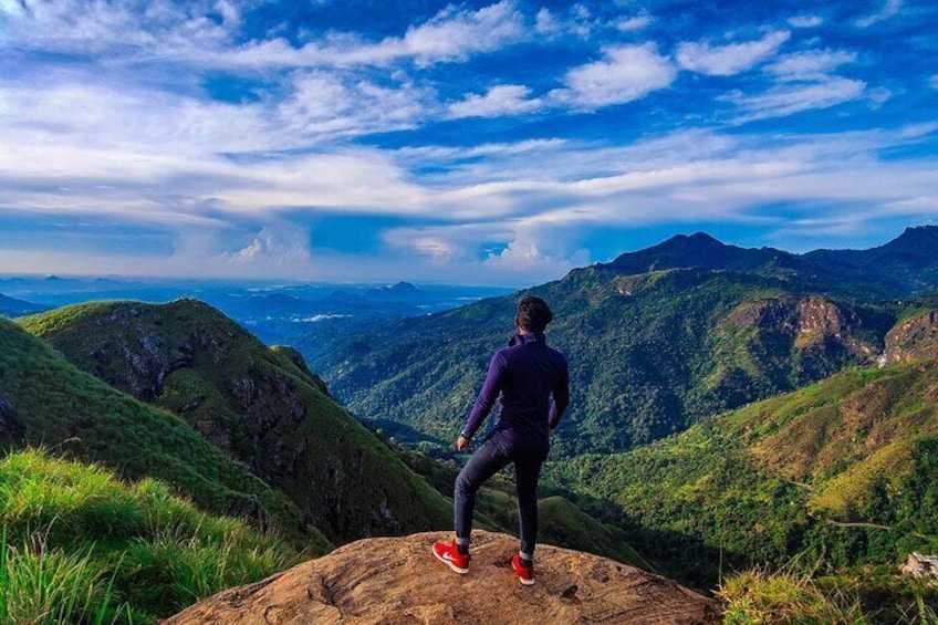 A person standing on a rock with a mountainous landscape in the background. 4