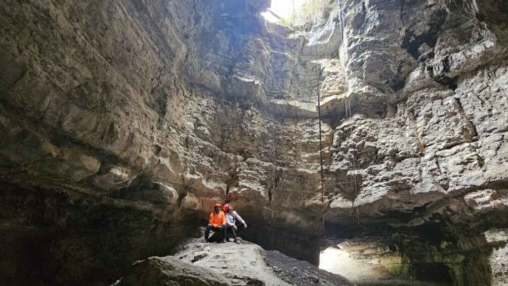A person sitting on a rock inside a narrow canyon with steep walls. 5
