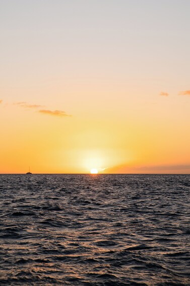 Een zonsondergang boven de oceaan, met een boot in de verte. 4
