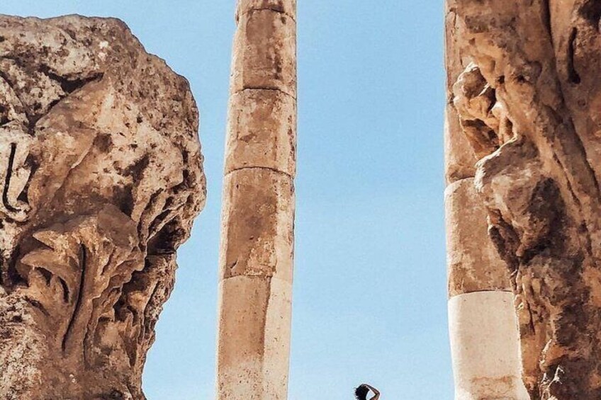 Columnas de piedra antiguas con adornos tallados, cielo despejado y una persona a lo lejos. 5