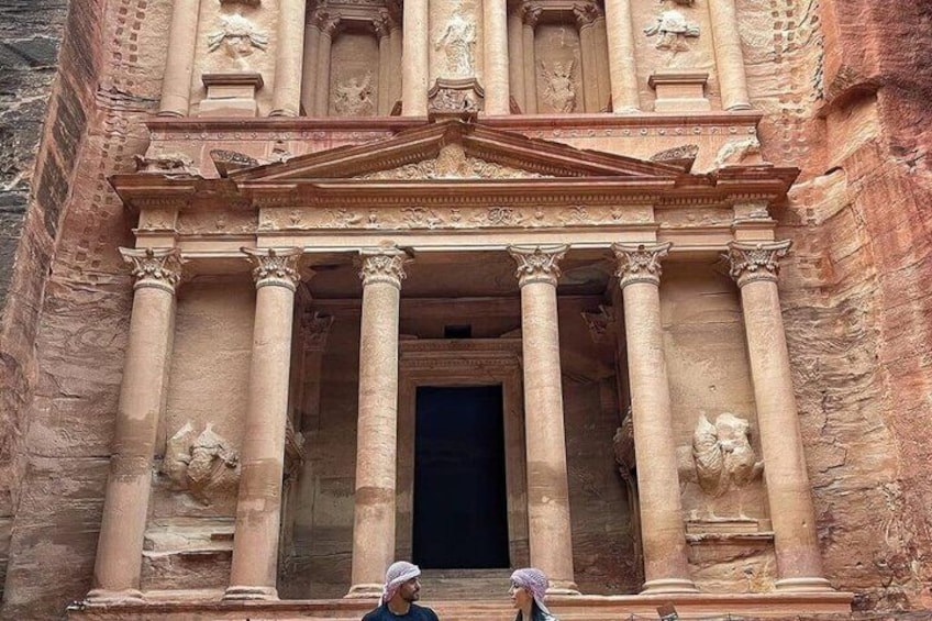 Un grand bâtiment ancien, doté d’une entrée imposante, flanqué de colonnes et orné de sculptures détaillées. 1