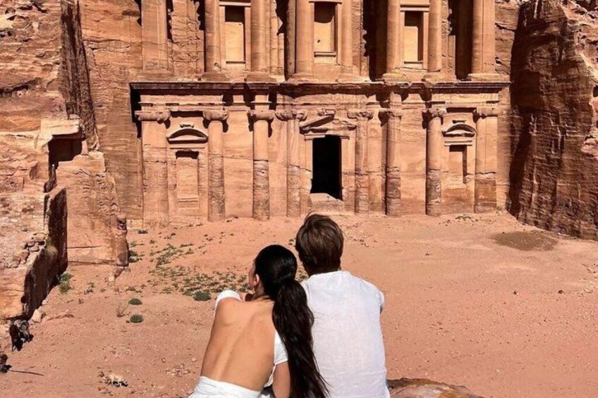 A couple standing in front of a large ancient sandstone structure with columns and a doorway. 3