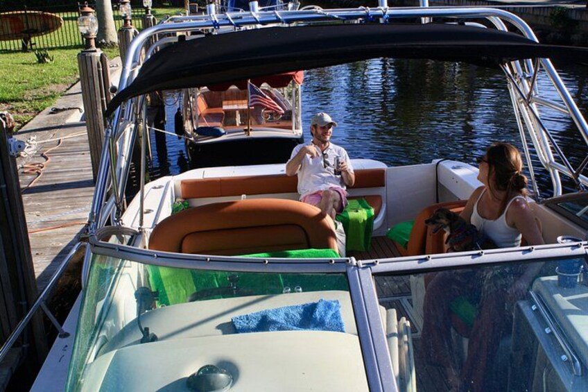 A boat with a covered top, a person sitting on the deck, and another person standing. 5