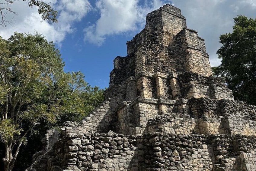 Una estructura piramidal de piedra rodeada de árboles. 4