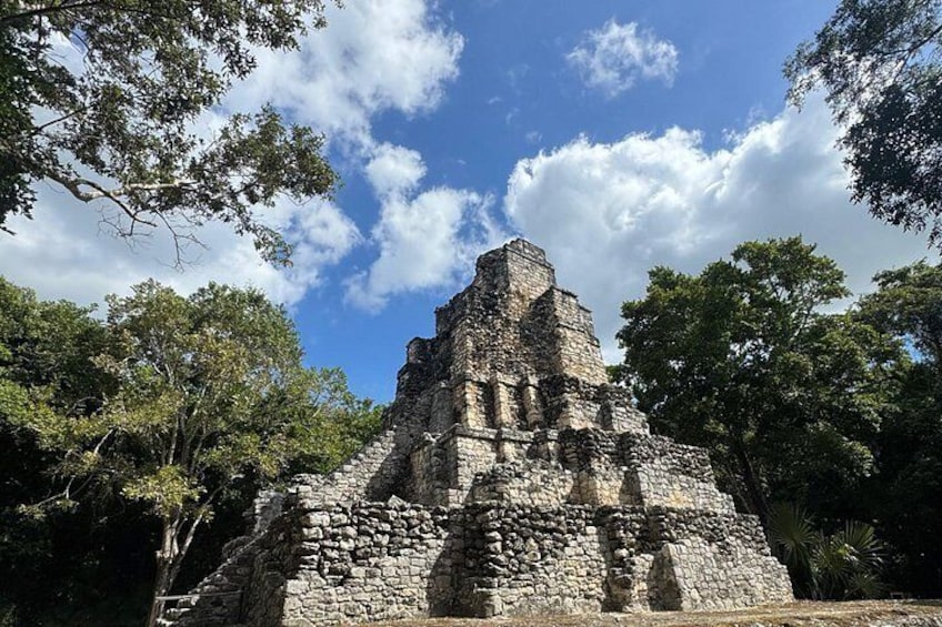 Una estructura piramidal de piedra rodeada de árboles. 3