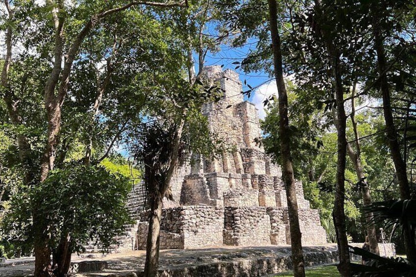 Una estructura de piedra antigua rodeada de árboles. 2