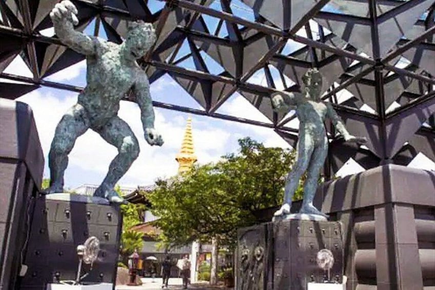 To bronzestatuer af mænd på sokler, et gyldent spiret i baggrunden og en metalkonstruktion. 5