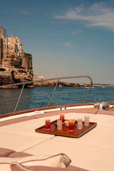 A boat with a tray of drinks and a view of rocky cliffs and calm water. 5