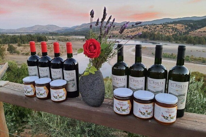 Ein malerischer Ausblick mit einer Holzwand, Flaschen El Poeta Wein, Honiggläser, eine rote Rose und eine Vase Lavendel. 4