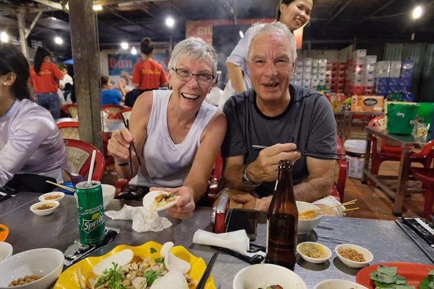 Un comedor con gente comiendo, una botella de cerveza y diversos platos en la mesa. 1