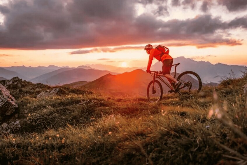 A mountain biker on a trail with a sunset in the background. 1