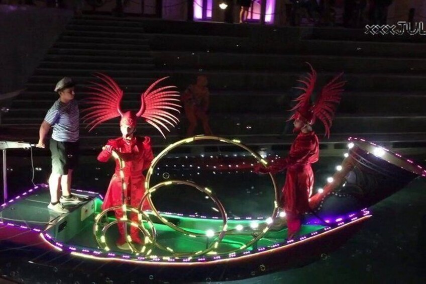 Un artista con un traje rojo y grandes alas sobre un escenario con una disposición de luces circulares. 2