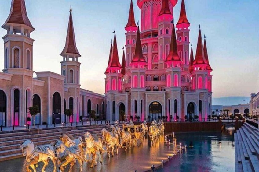 A castle with multiple spires, a fountain with horse statues, and a body of water. 5