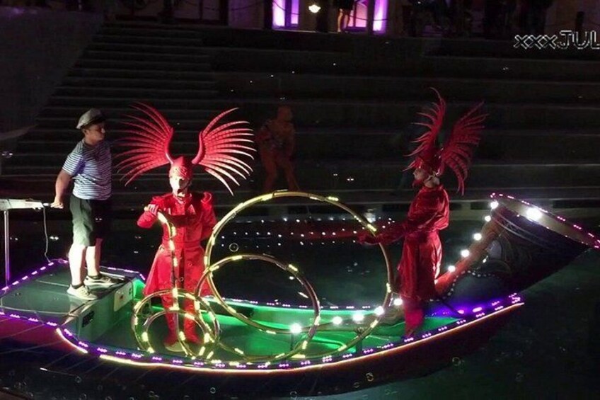 Un escenario con artistas vestidos de rojo e iluminación circular. 2