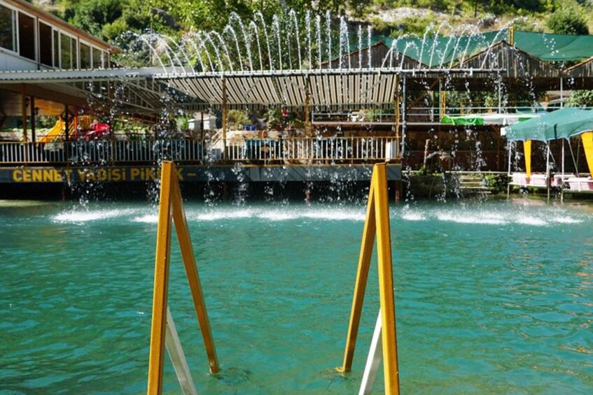 A water fountain with a wooden deck and a boat in the background. 2