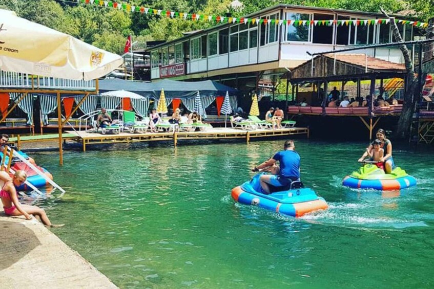 People on inflatable rafts in a water park with a dock and umbrellas. 1