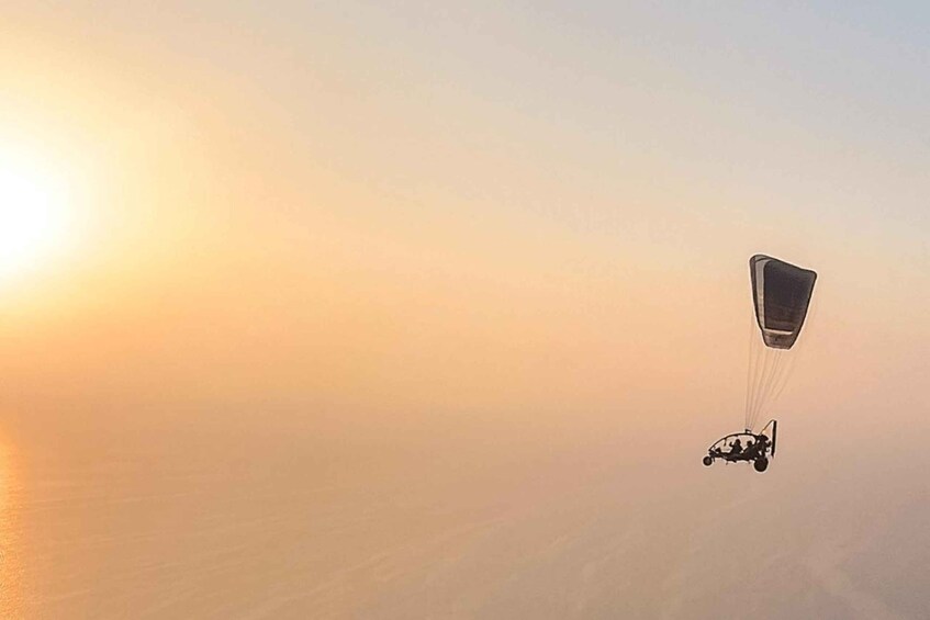 A paraglider in mid-flight during sunset. 3