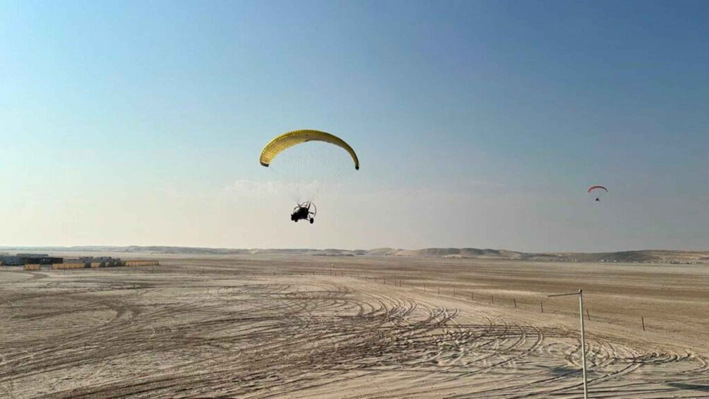 A desert landscape with two paragliders and a helicopter. 5