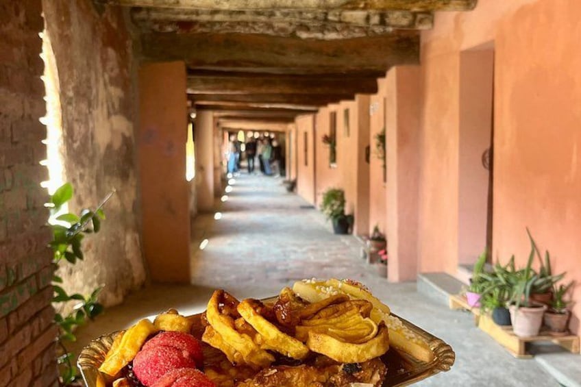 Un corridoio con un tavolo imbandito di cibo, tra cui pancake e fragole, in un edificio con pareti in mattoni e piante in vaso. 5
