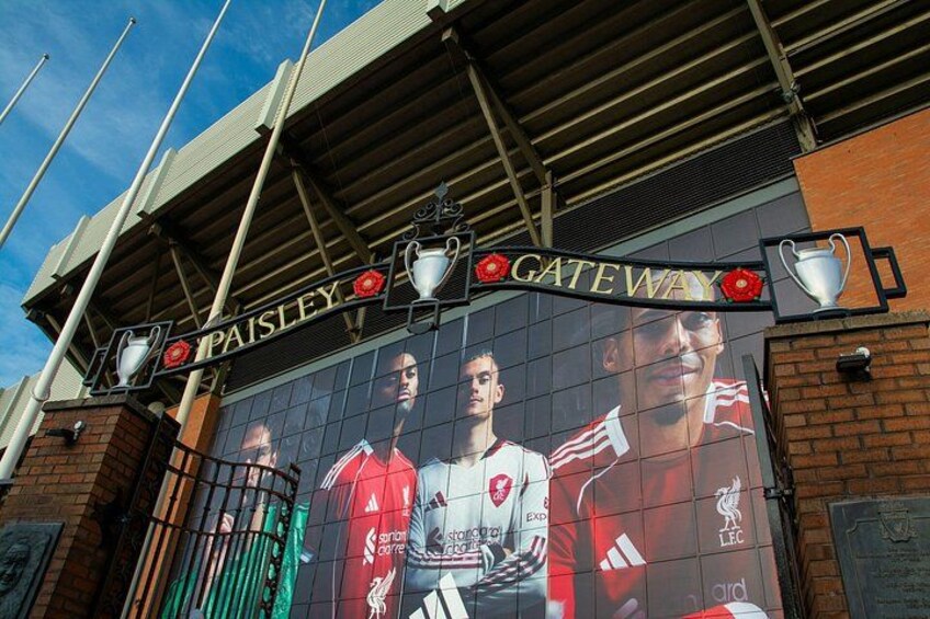 A stadium entrance with a mural of football players, the words 'PAISLEY' and 'GATEWAY' above, and a trophy on the right. 1