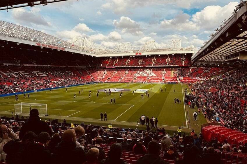 A football stadium with a green pitch, goalposts, and a crowd of spectators. 3