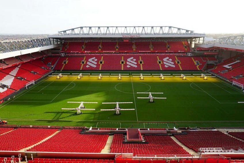 A stadium with red seating and a green field. 2