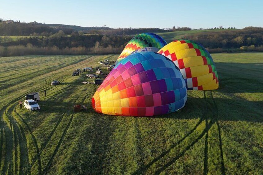 Globos aerostáticos coloridos sobre un campo cubierto de hierba, con vehículos y un paisaje montañoso al fondo. 3