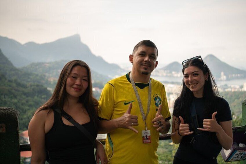 Three people standing with a mountainous landscape in the background. 1