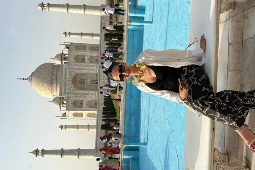 A person standing in front of the Taj Mahal with a pool in the background. 3
