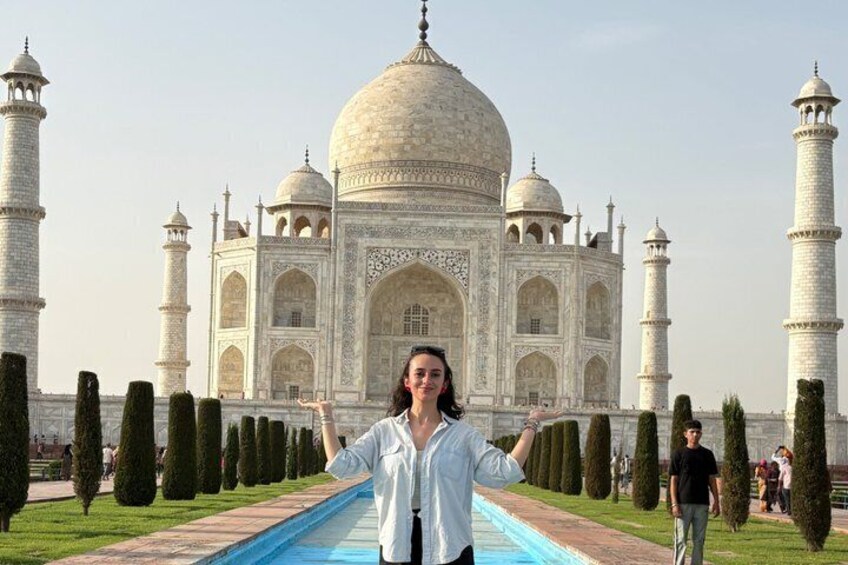 A person standing in front of the Taj Mahal with arms outstretched. 4