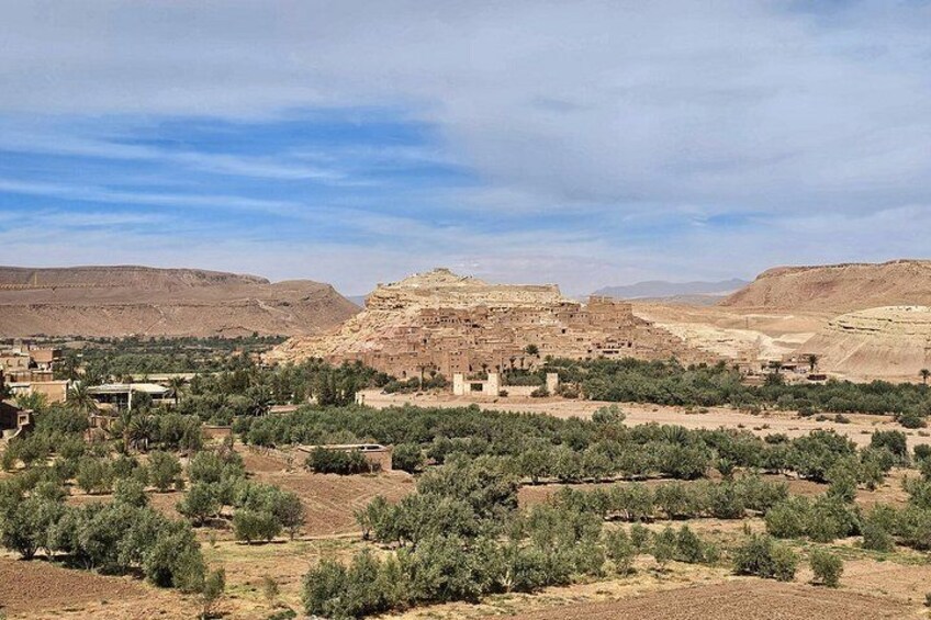A desert landscape with a prominent ancient ruin in the center, surrounded by sparse vegetation and distant hills. 2
