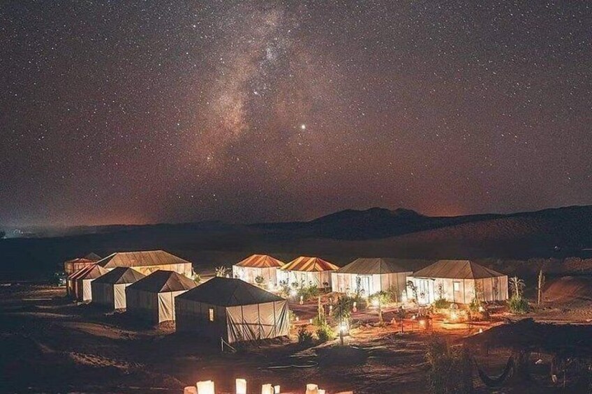 A desert landscape at night with multiple yurts illuminated by artificial lights. 5
