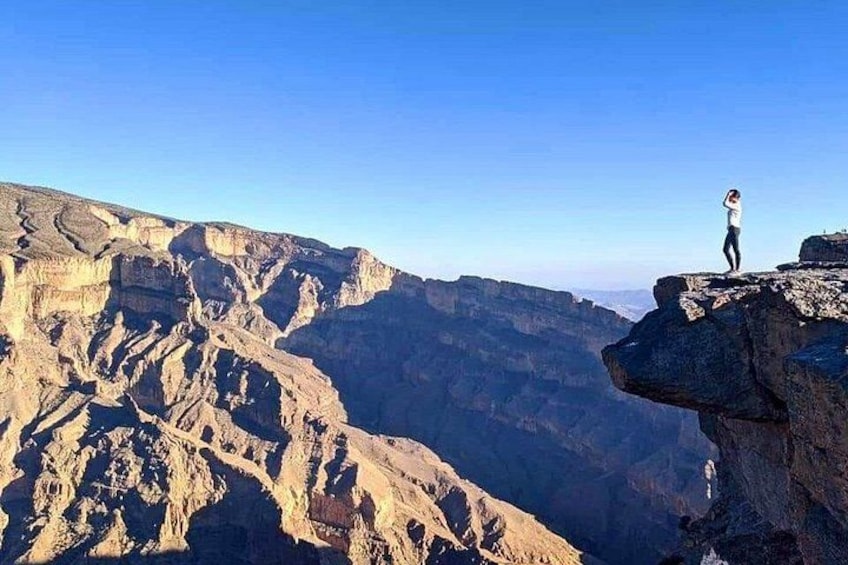 A person standing on a cliff edge overlooking a canyon. 3