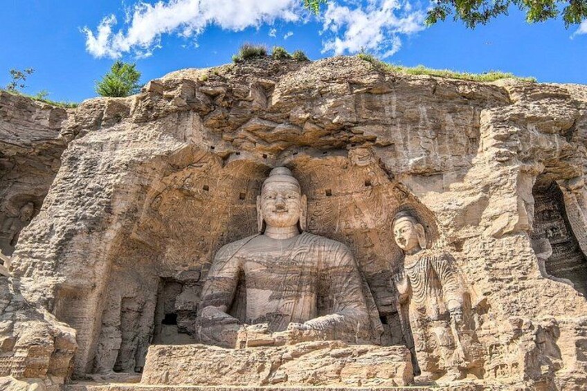 A large Buddha statue carved into a cliff face, with a smaller figure beside it. 1