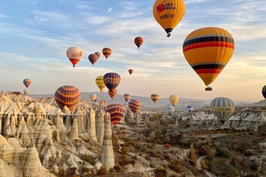 A landscape with numerous hot air balloons in the sky and distinctive white rock formations below. 2
