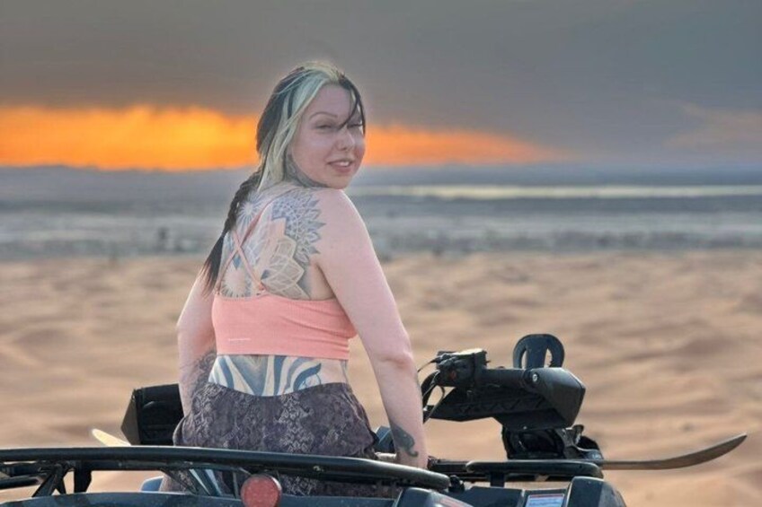 Eine Person fährt mit einem Quad am Strand, im Hintergrund ein Sonnenuntergang. 3