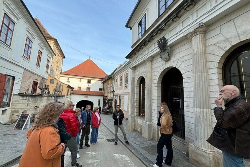 Eine Gruppe von Menschen geht auf einer Kopfsteinpflasterstraße entlang, historisches Gebäude im Hintergrund, und ein klarer Himmel. 4