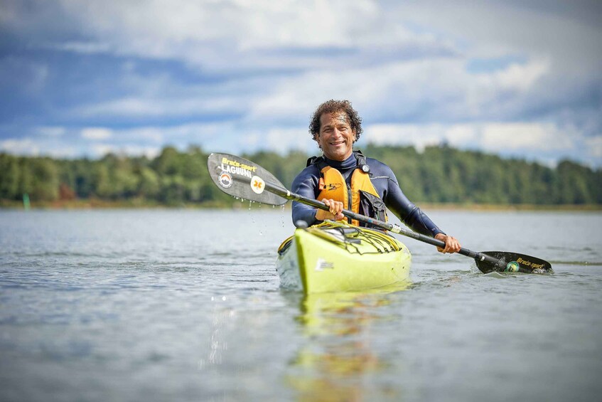 A person kayaking on a calm lake with a forest in the background. 5