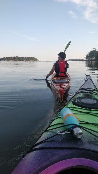 A person kayaking on calm water with a forested island in the background. 3