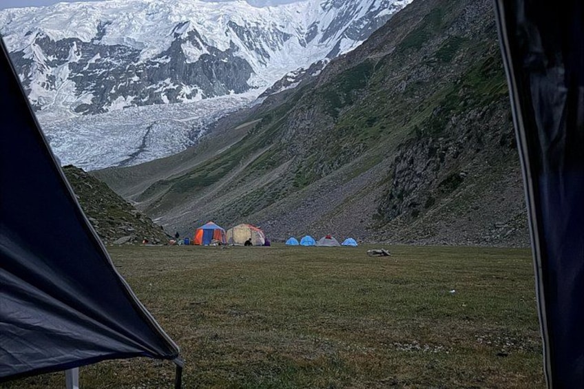 A mountainous landscape with tents and a glacier in the background. 3