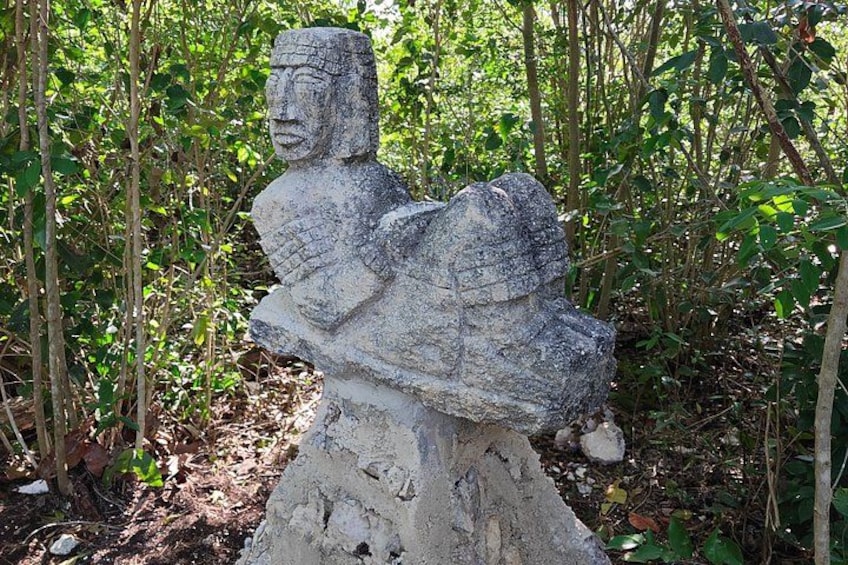 En stenhugget figur i et skovområde. 4