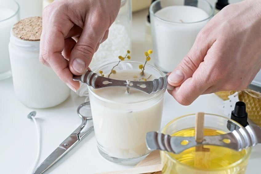 Hands holding a spoon with a metal handle, a glass jar, and a candle. 1