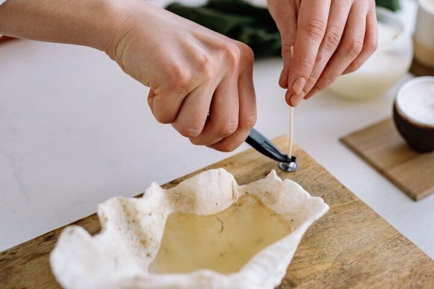 A person using a tool to cut a white object on a wooden board. 3
