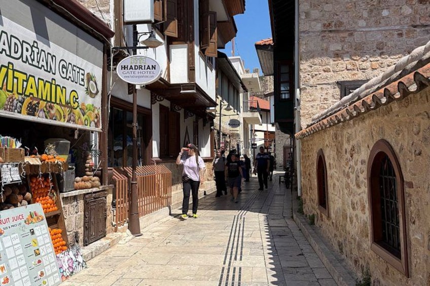 A narrow street with shops, a sign for 'ADRIAN GATE VITAMIN C', and a 'HAIDRIAN CAFE HOTEL'. 3