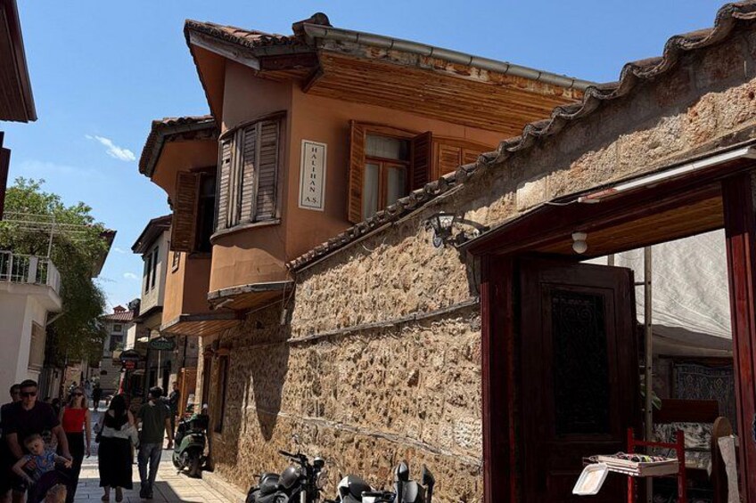 A narrow street with stone buildings, a motorcycle parked on the side, and a few pedestrians. 2
