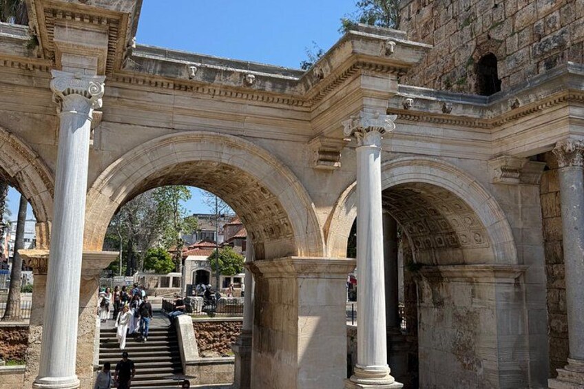 An ancient stone archway with columns, leading to a staircase and a building in the background. 4