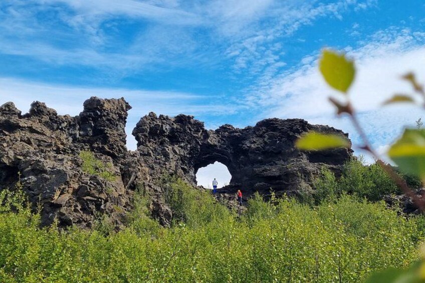 En naturlig klippeformation med en stor bue, omgivet af grønt og under en klar himmel. 4