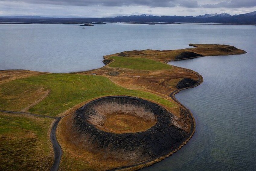 A coastal landscape with a large crater-like formation surrounded by water. 5