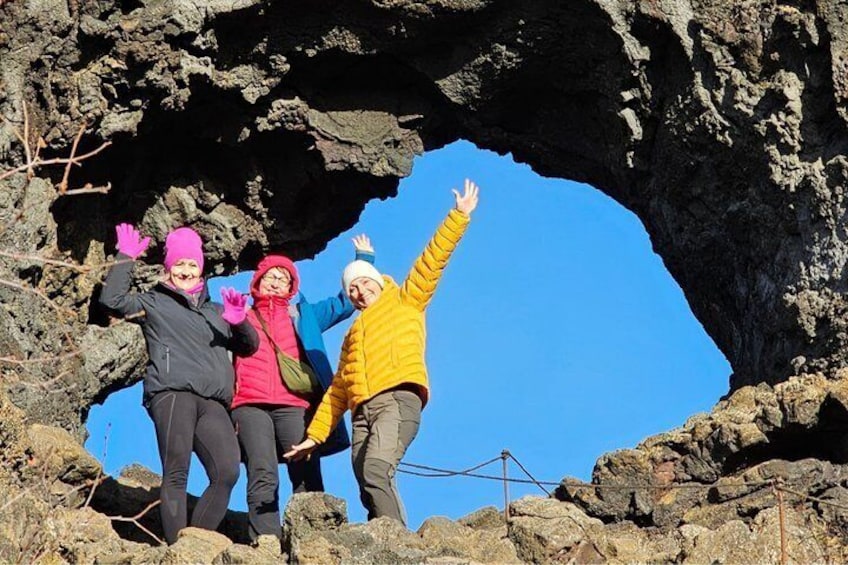 Three people standing in a rocky arch formation. 4